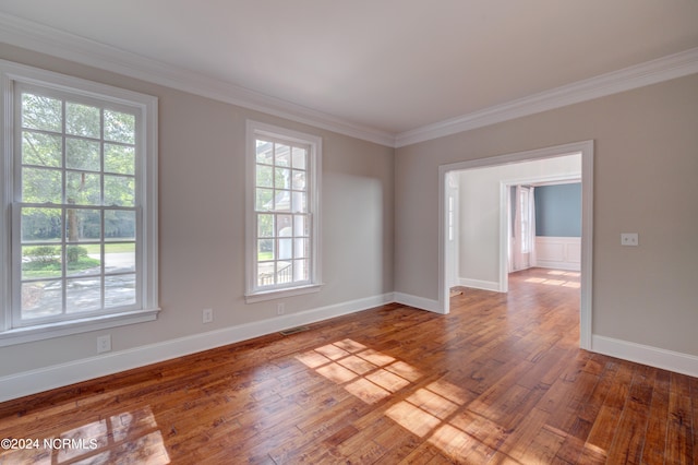 spare room with crown molding, hardwood / wood-style floors, and plenty of natural light