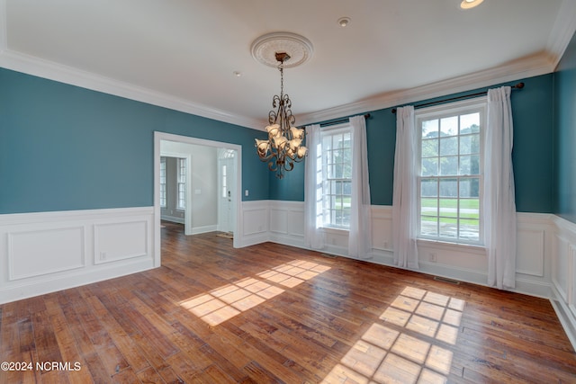 empty room with wood-type flooring, crown molding, and a chandelier