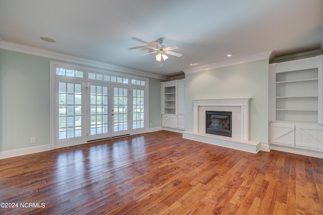 unfurnished living room with ceiling fan, crown molding, hardwood / wood-style floors, and built in shelves