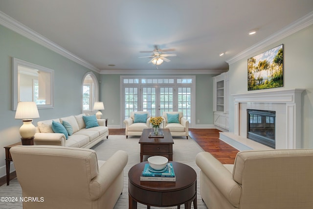 living room featuring light hardwood / wood-style flooring, built in features, ceiling fan, and crown molding