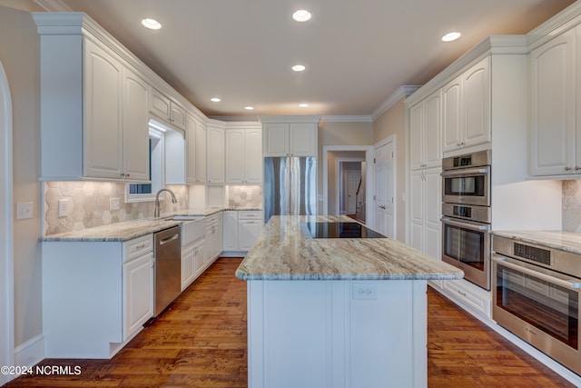 kitchen with white cabinets, a kitchen island, wood-type flooring, stainless steel appliances, and light stone countertops