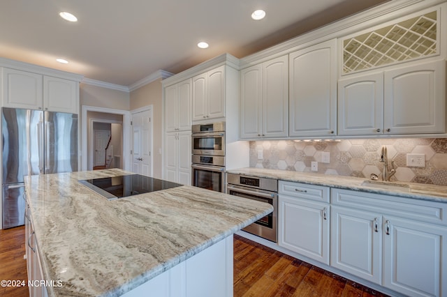 kitchen featuring light stone countertops, white cabinets, a kitchen island, and stainless steel appliances