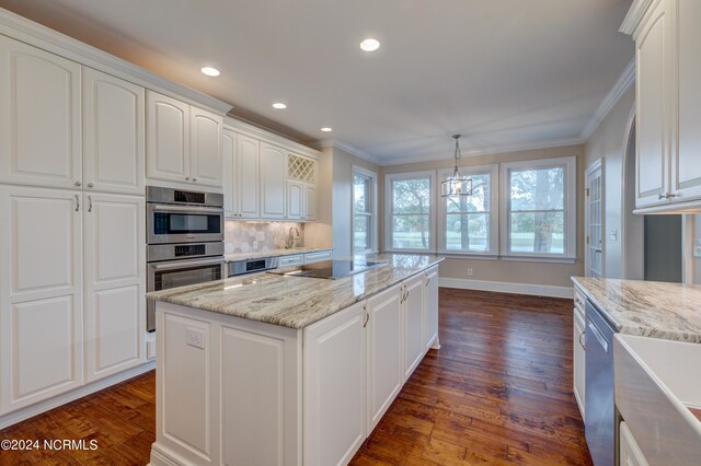 kitchen featuring hanging light fixtures, crown molding, a center island, and white cabinets