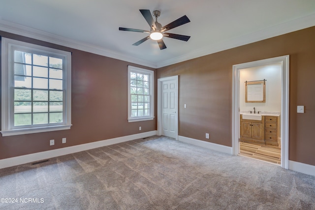 unfurnished bedroom with ornamental molding, connected bathroom, multiple windows, and ceiling fan