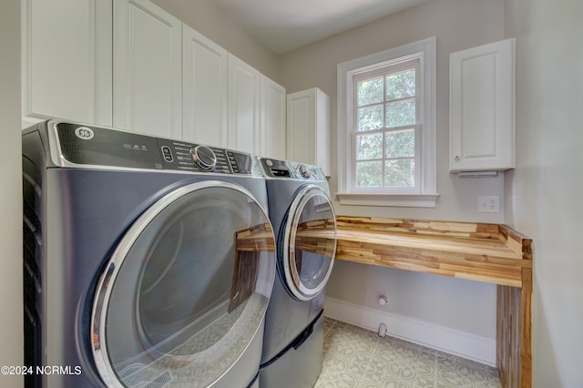 clothes washing area with light tile patterned floors, washing machine and clothes dryer, and cabinets