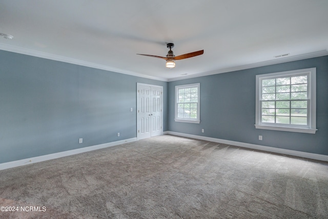 carpeted empty room with a wealth of natural light, ceiling fan, and crown molding