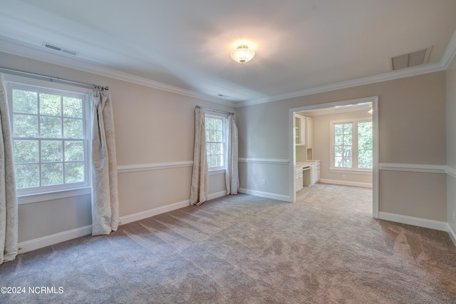 spare room with ornamental molding, a wealth of natural light, and light colored carpet