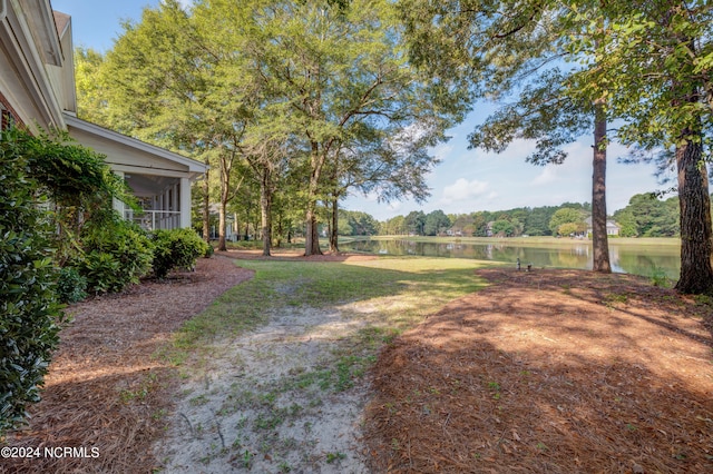 view of yard featuring a sunroom and a water view