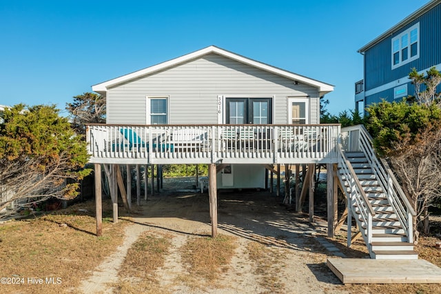 3016 W Beach Dr, Oak Island, NC 28465 - back of property with a carport, a deck, driveway, stairway, and french doors