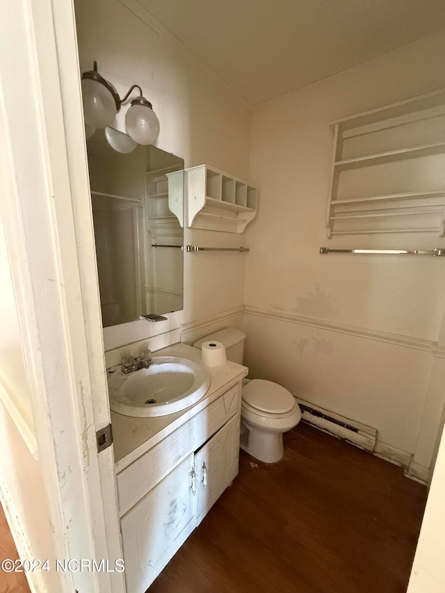 bathroom with hardwood / wood-style floors, vanity, toilet, and a baseboard heating unit