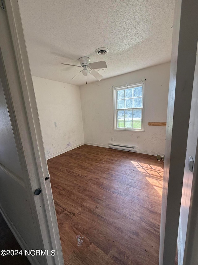 empty room featuring a textured ceiling, ceiling fan, dark wood-type flooring, and a baseboard radiator