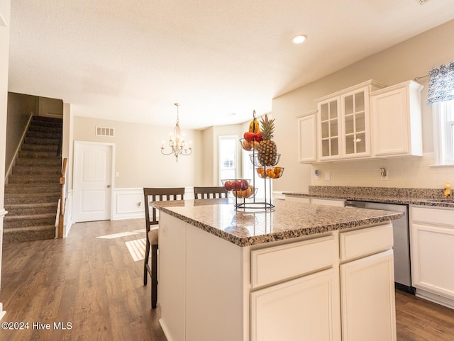 kitchen with wood-type flooring, a kitchen island, a healthy amount of sunlight, and light stone counters