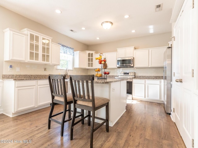 kitchen with white cabinets, a kitchen bar, and appliances with stainless steel finishes