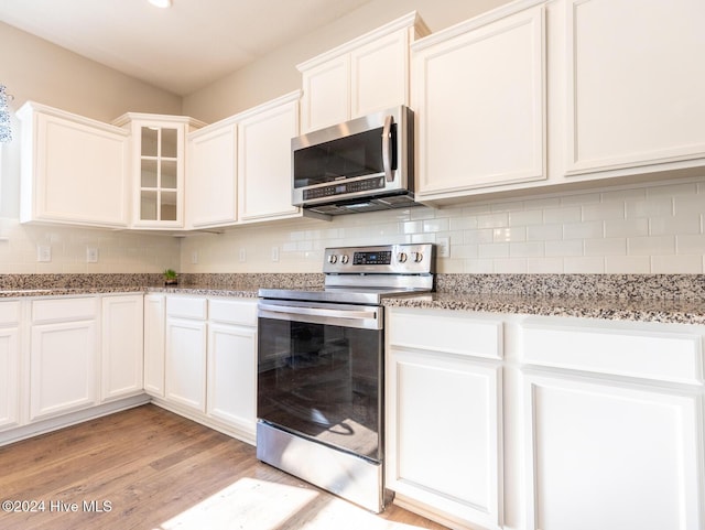 kitchen featuring light stone countertops, appliances with stainless steel finishes, light hardwood / wood-style floors, and white cabinetry