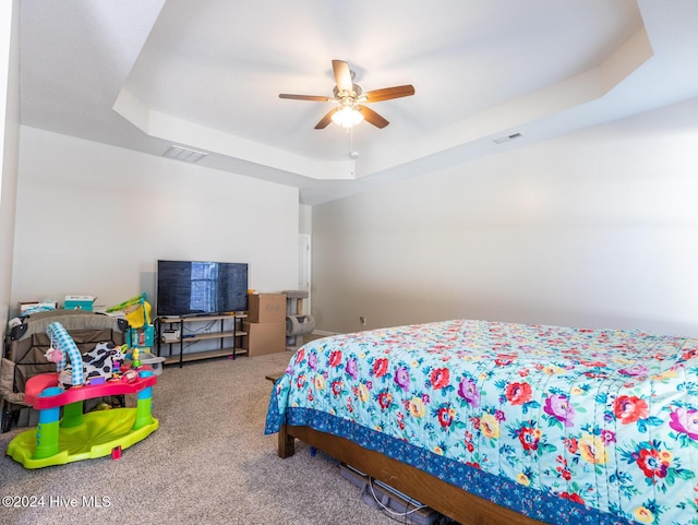 bedroom with carpet flooring, a raised ceiling, and ceiling fan