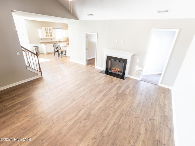 unfurnished living room with light hardwood / wood-style floors and lofted ceiling