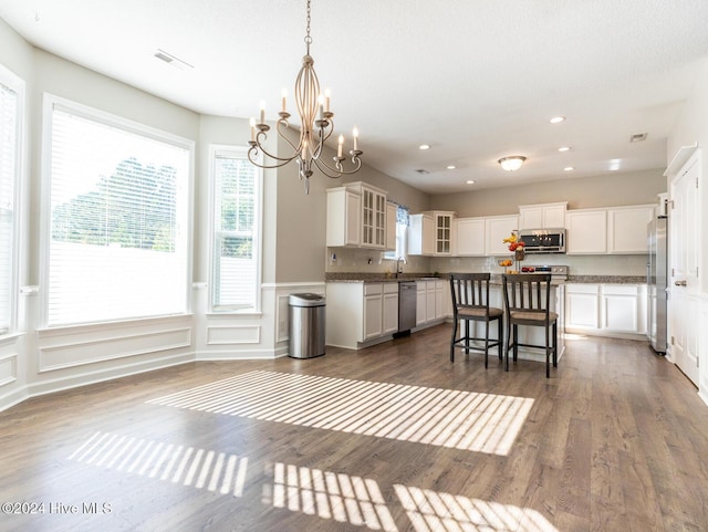 kitchen featuring stainless steel appliances, a kitchen island, dark hardwood / wood-style flooring, a breakfast bar area, and white cabinets