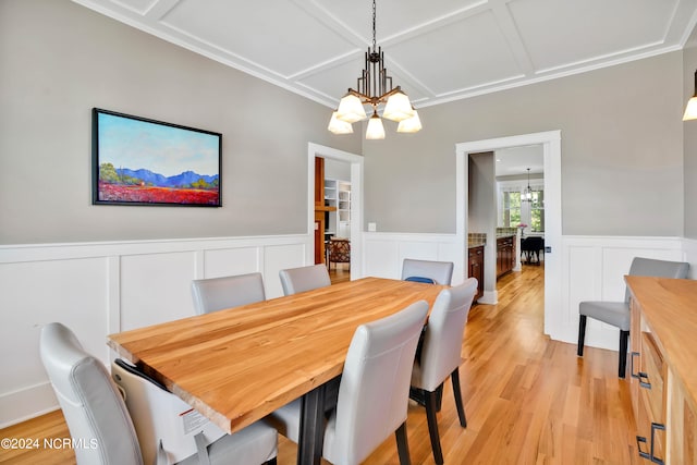 dining room featuring coffered ceiling, light wood-type flooring, and a chandelier