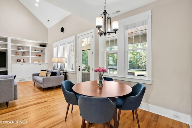 dining area featuring light hardwood / wood-style floors, a chandelier, and high vaulted ceiling