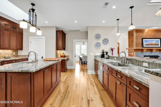 kitchen with light wood-type flooring, dishwasher, decorative light fixtures, and sink