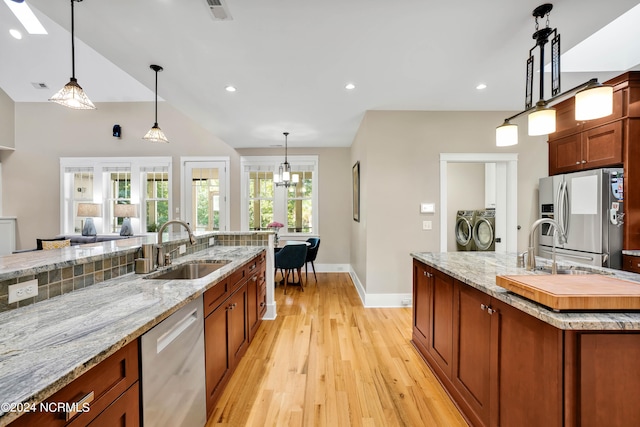 kitchen with washing machine and clothes dryer, appliances with stainless steel finishes, hanging light fixtures, and sink