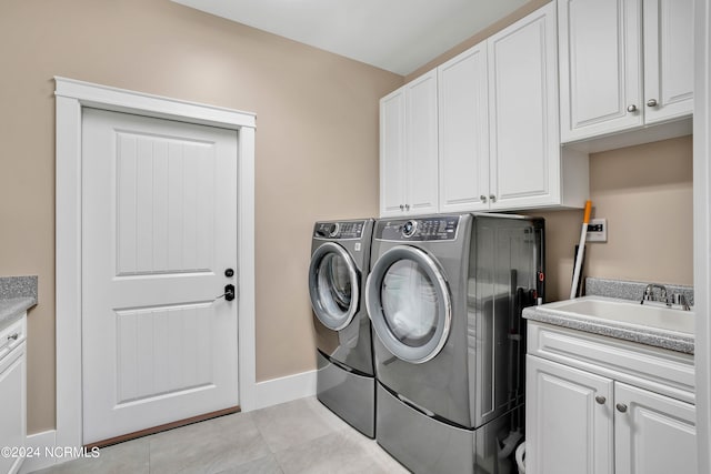 laundry room featuring cabinets, washing machine and clothes dryer, light tile patterned floors, and sink