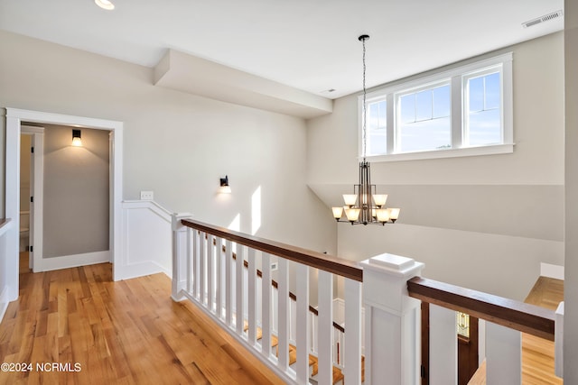 corridor featuring light hardwood / wood-style floors and an inviting chandelier