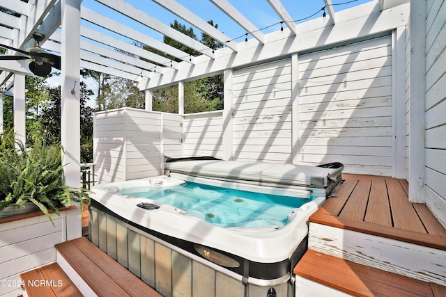 wooden deck featuring a pergola and a covered hot tub