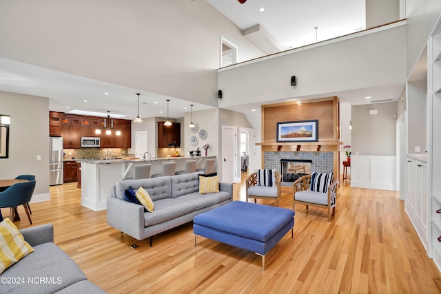 living room featuring a towering ceiling, light hardwood / wood-style floors, and a tile fireplace