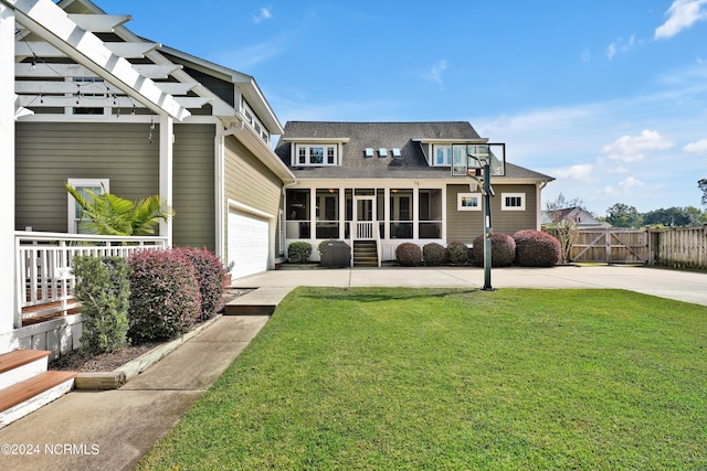 rear view of house with a lawn, a sunroom, and a garage