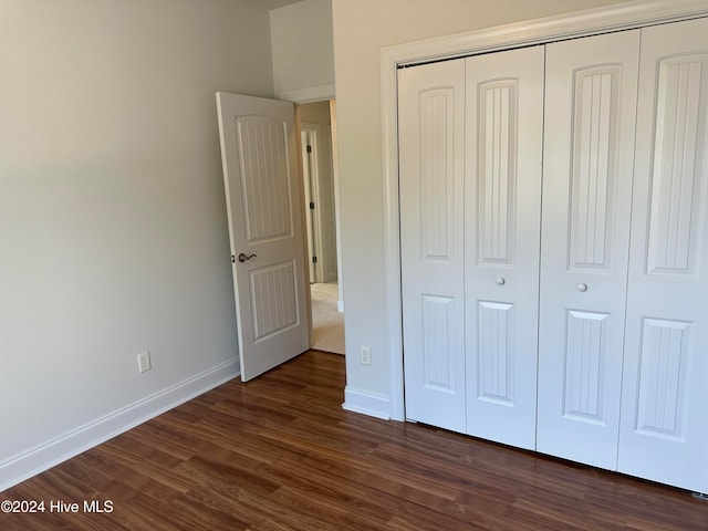 unfurnished bedroom with dark hardwood / wood-style floors and a closet