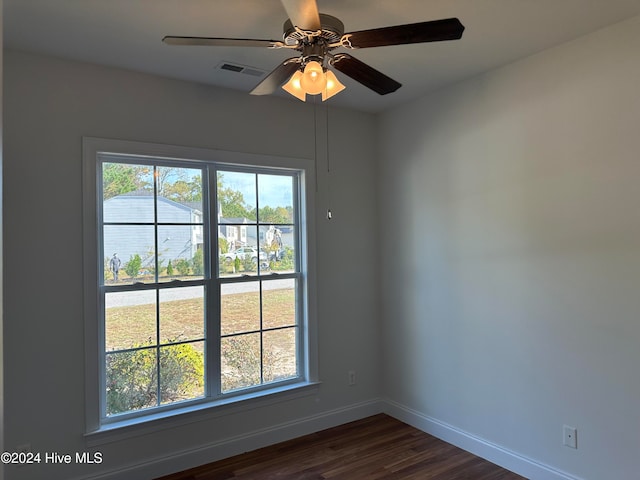 empty room with a wealth of natural light, ceiling fan, and dark hardwood / wood-style flooring