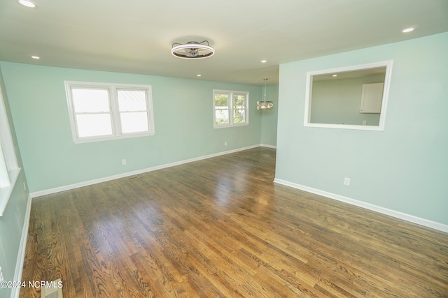 unfurnished room with a chandelier and dark wood-type flooring