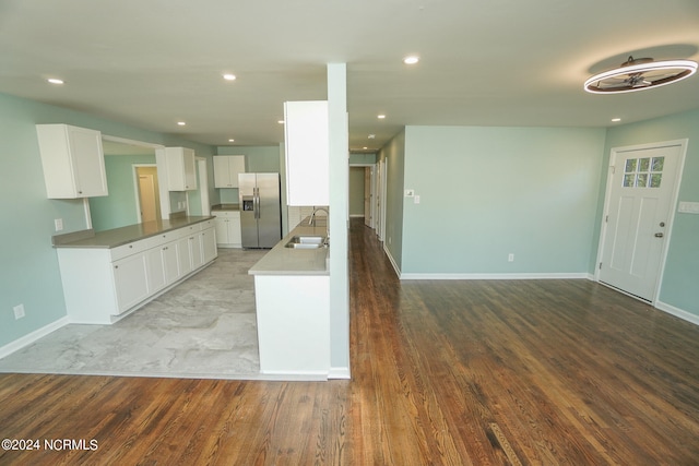 kitchen with light hardwood / wood-style flooring, stainless steel fridge, sink, and white cabinetry