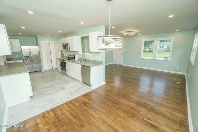 kitchen with stainless steel appliances, white cabinetry, light wood-type flooring, and sink