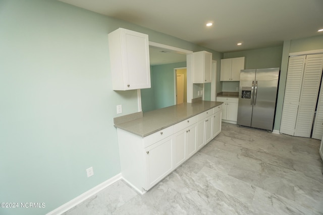 kitchen featuring stainless steel fridge and white cabinetry