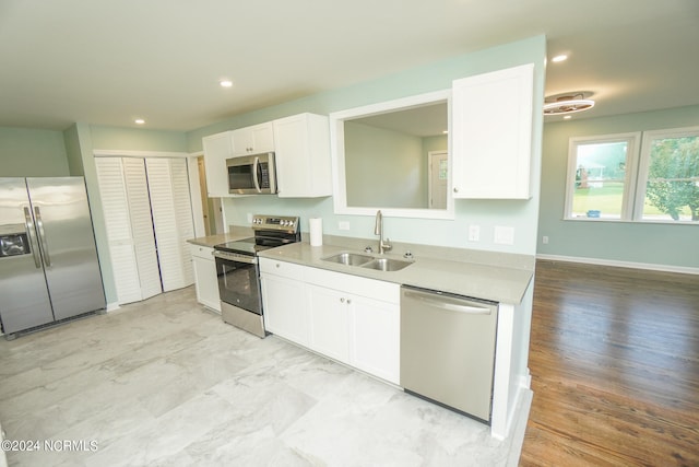 kitchen featuring appliances with stainless steel finishes, light wood-type flooring, sink, and white cabinets