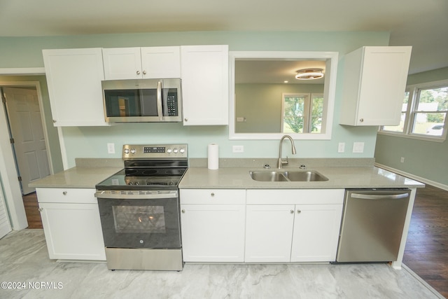 kitchen featuring appliances with stainless steel finishes, light wood-type flooring, white cabinetry, and sink