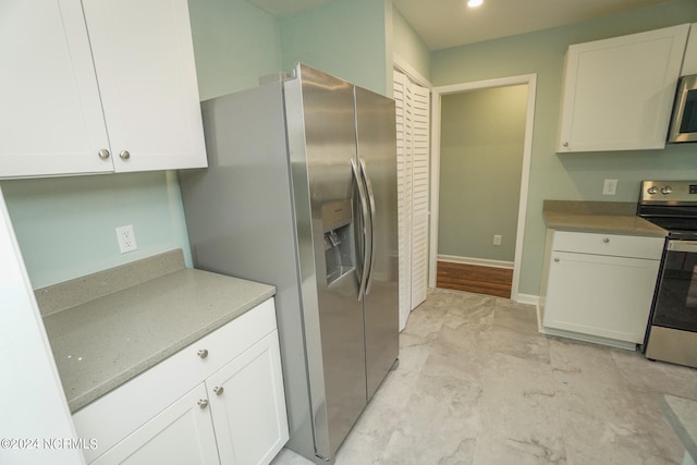 kitchen featuring appliances with stainless steel finishes, light stone countertops, and white cabinets