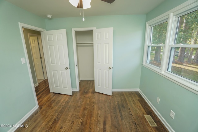 unfurnished bedroom with dark hardwood / wood-style floors, ceiling fan, and a closet