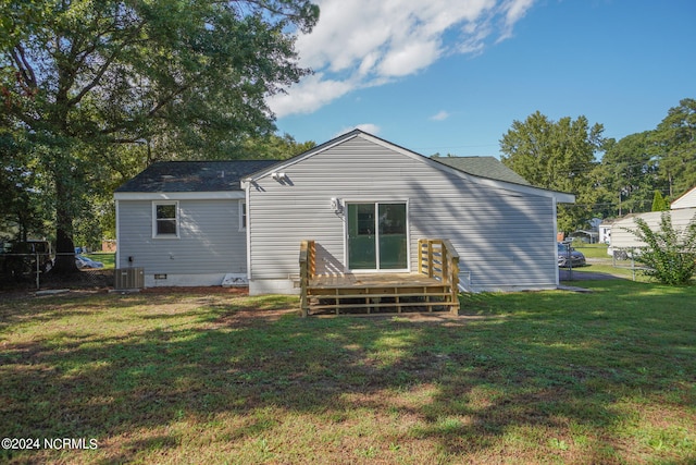 rear view of property featuring central AC unit and a lawn