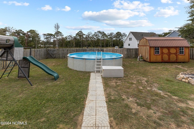 view of pool with a playground, a storage unit, and a yard