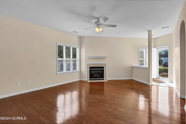 unfurnished living room with ceiling fan, dark hardwood / wood-style flooring, and a tile fireplace