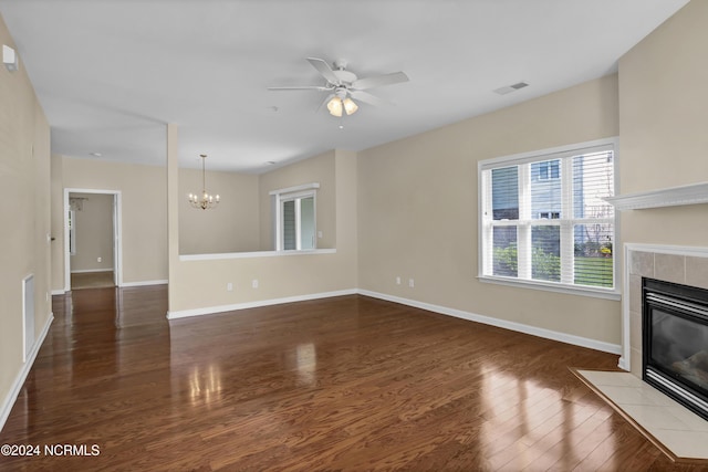 unfurnished living room featuring visible vents, a fireplace, wood finished floors, baseboards, and ceiling fan with notable chandelier