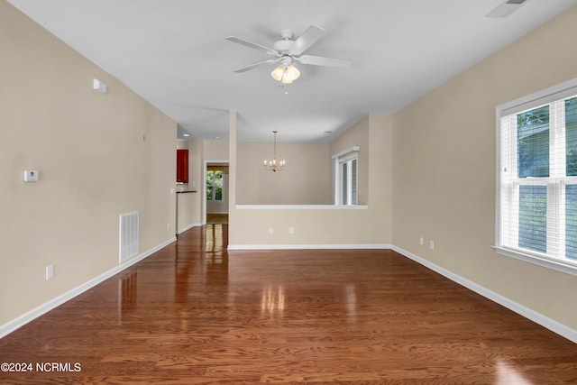 empty room with dark hardwood / wood-style floors and ceiling fan with notable chandelier