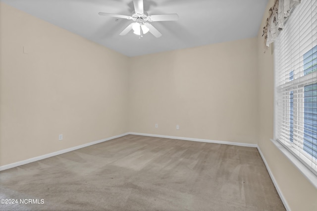 spare room featuring plenty of natural light, a ceiling fan, carpet, and baseboards
