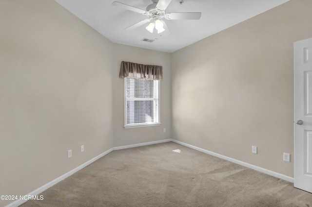 carpeted empty room with baseboards, ceiling fan, and visible vents