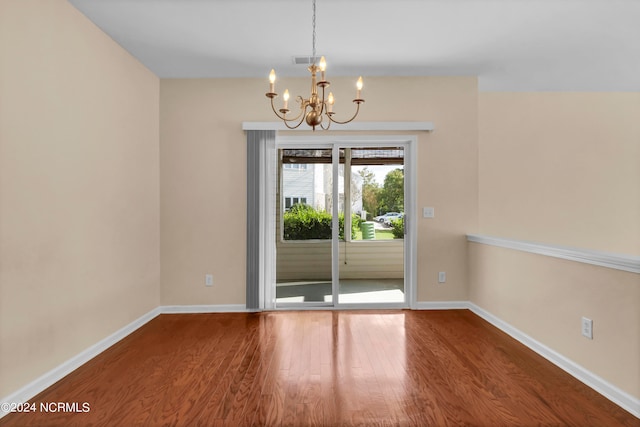 unfurnished dining area with hardwood / wood-style floors and a notable chandelier