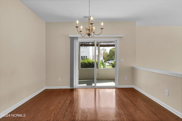unfurnished dining area with baseboards, a notable chandelier, wood finished floors, and visible vents