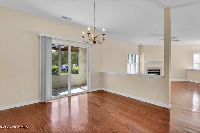 spare room featuring hardwood / wood-style floors and ceiling fan with notable chandelier